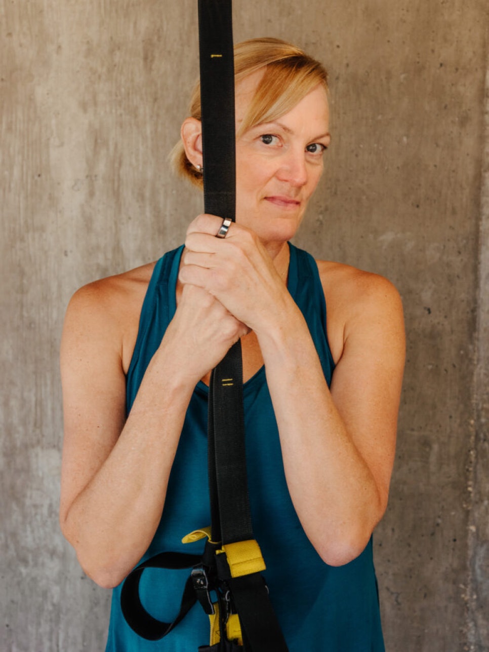 A woman holding a belt harness and wearing an Oura ring.