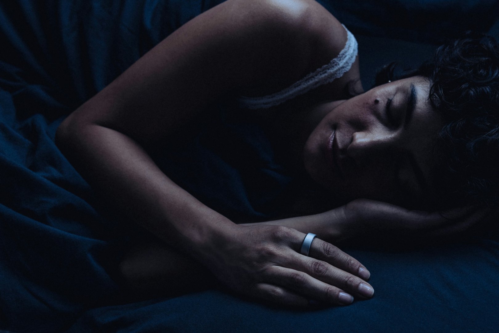 Woman sleeping while wearing a brushed silver Oura Ring 4