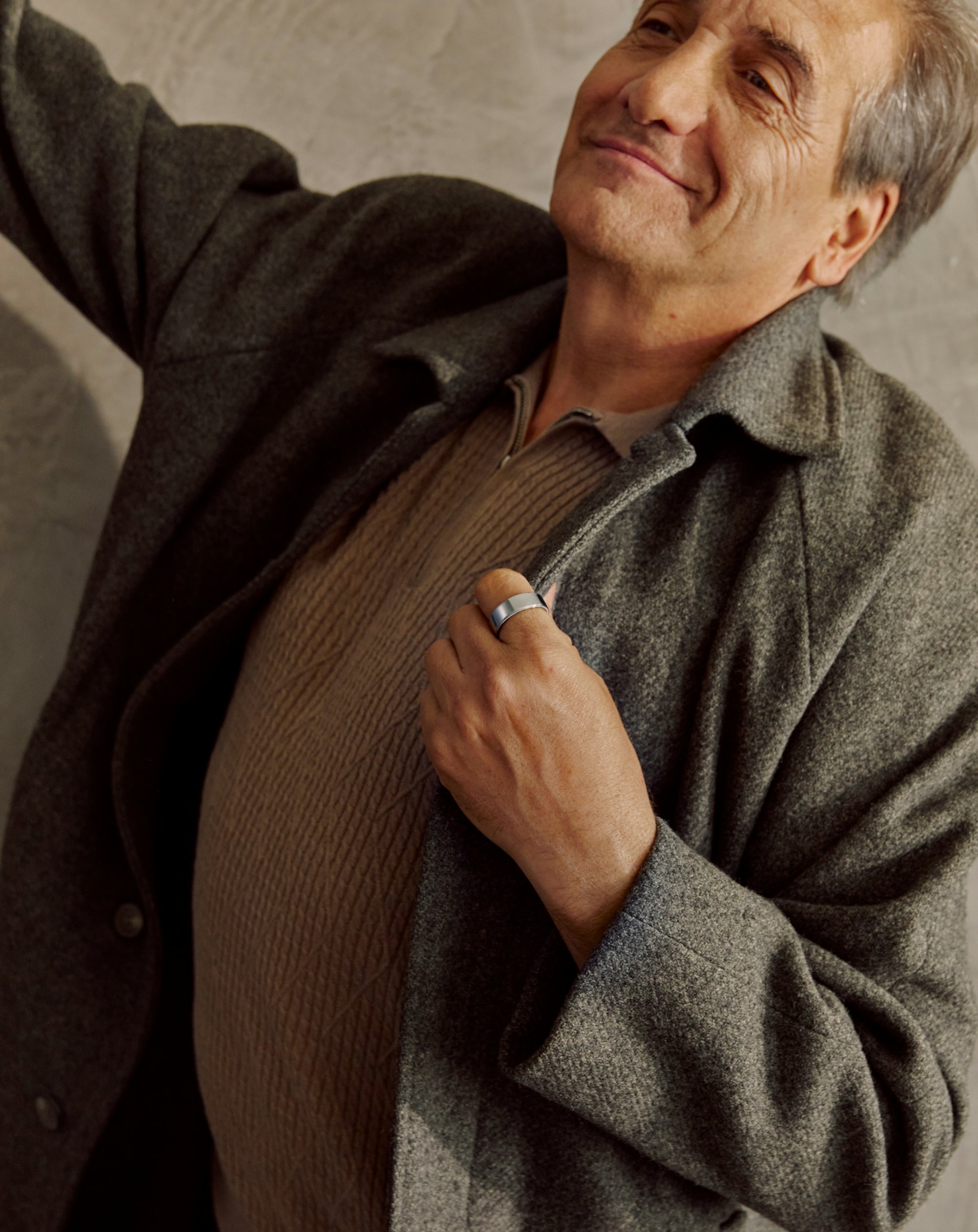 A man holding the lapel of his jacket and wearing an Oura ring.