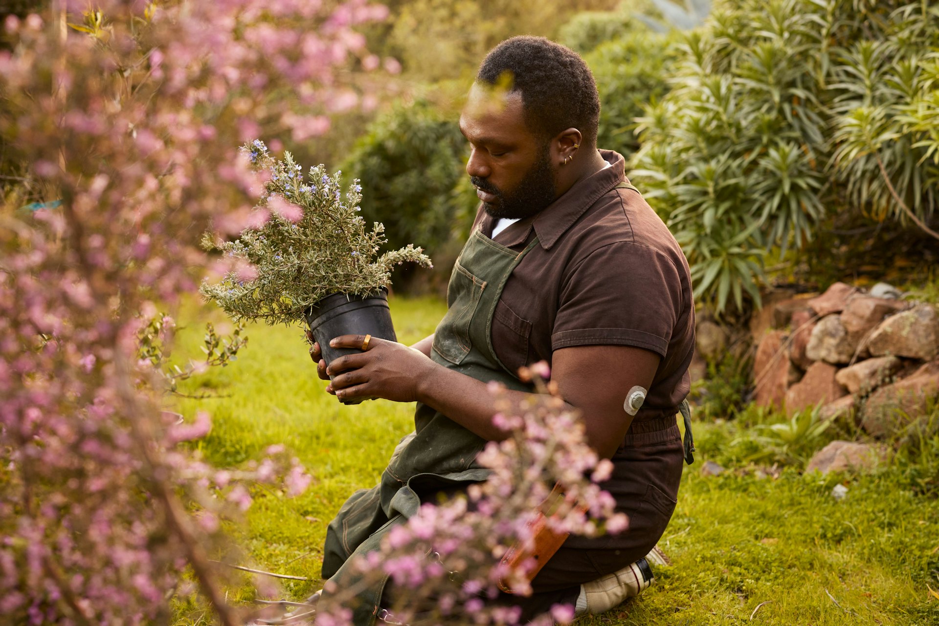 A man holding a potted plant with an Oura Ring on his left index finger.